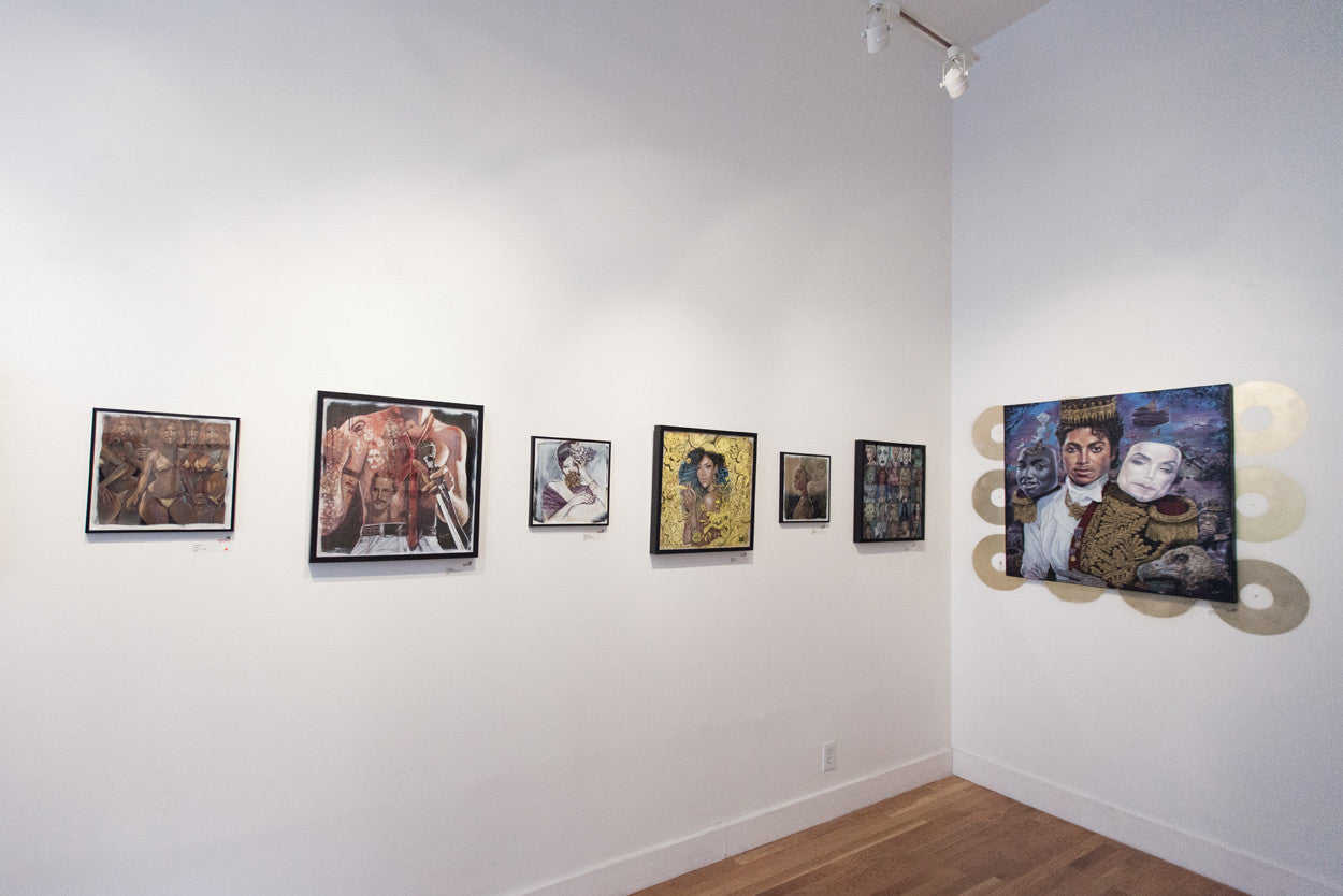 A gallery wall features six framed artworks in diverse portrait and abstract styles, with the largest piece inspired by the Serge Gay Jr. brand depicting a couple. The room, with its elegant wooden floors and white walls, showcases varying themes and colors.