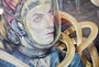 A Serge Gay Jr. painting shows an astronaut looking at Mars, surrounded by swirling yellow ribbons and celestial bodies, capturing a cosmic theme in his dreamlike style.