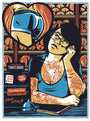 A tattooed woman with glasses leans on a counter, surrounded by bakery-themed signs and items, in this screenprint by Jeffrey Everett/Rockets are Red. She appears contemplative, evoking Bobs Burgers, with Everetts signature touch highlighted by a bell on the counter near her.