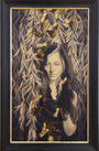 The sepia portrait of a woman with dark hair, adorned with cascading leaves and golden butterflies, embodies an Alessandra Maria masterpiece. Gold leaf details add charm and color as she gazes softly—a striking piece echoing the Beyond Eden Art Fairs ethereal allure.