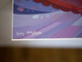 Close-up of a Dave MacDowell fine art giclee print with abstract purple and pink brushstrokes and red dots, signed DM and numbered 100/100 in white at the bottom left corner.