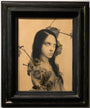 A framed artwork by Alessandra Maria features a solemn figure with long dark hair, surrounded by flowers and butterflies on a neutral background. The blend of realistic and surreal elements enhances its enigmatic mood, reminiscent of pieces at Spoke Art.