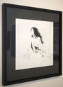 Tangling Wind, a framed black and white sketch by M Ian Dringenberg, beautifully captures a woman in a robe with her hair flowing. This ink-on-paper piece emphasizes her relaxed pose and is elegantly displayed on a white wall.