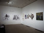 In a modern art gallery, walls adorned with vibrant abstract paintings and a bulls head-like sculpture in charcoal and graphite captivate visitors. Under spotlight-lit ceilings, Joel Phillips inspired illustrations of a cyclist and tent draw special attention.