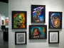 The art exhibit showcases framed paintings, including Jason Edmistons acrylic on wood panels of iconic sci-fi and horror characters like a robot, creature, and Wolf Man. Arranged elegantly in a structured display on a pristine white wall.