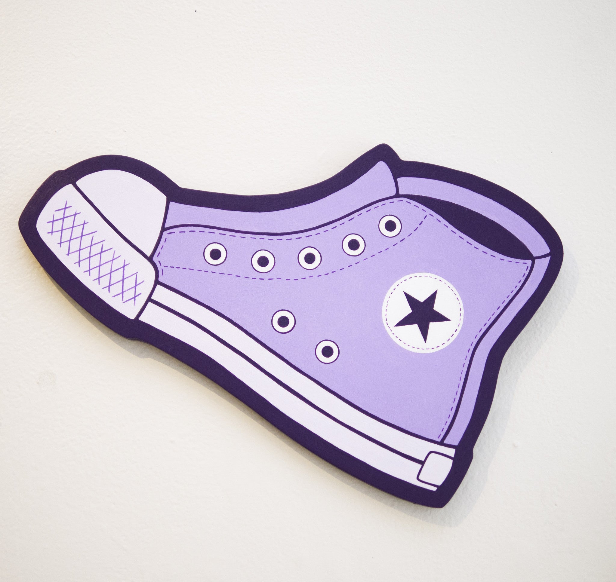 Illustration of Matt Ritchie’s purple high-top sneaker, similar to a classic Converse, with a black star on the side. It has white laces and stitching on a stark white background, with an outline evocative of hand-cut wood art detailed in bold black lines.