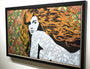 A framed artwork by Chuck Sperry, titled Olympia, features a woman with flowing orange hair set against a floral background, her body decorated with intricate designs that blend beautifully with the surrounding motifs.