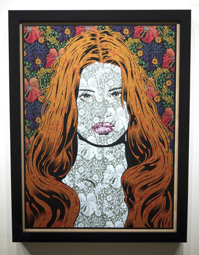 A Chuck Sperry framed screen print depicts a womans face with long red hair, intertwined with intricate floral designs on a Helikon-inspired background, blending her features with vibrant flowers.