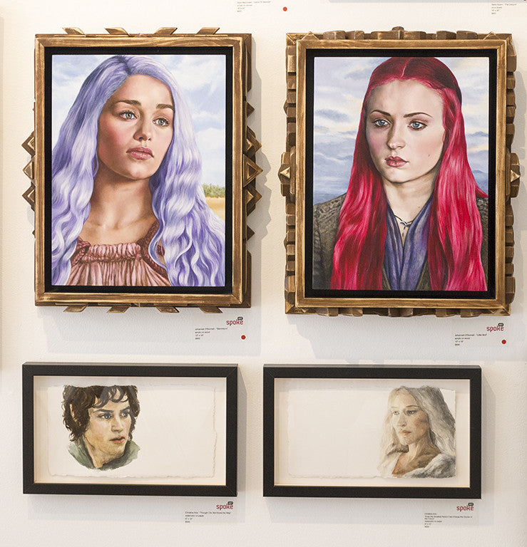 Four framed portraits hang on a wall; the top two, styled by Christine Aria, showcase women with pastel purple and bright red hair. Below, smaller frames feature a man with curly hair and a woman with long hair, both set against a white backdrop.