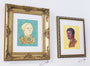 Two PJ McQuade framed portraits adorn a wall; the left portrays a person in armor against blue, reminiscent of Brienne of Tarth, and the right features someone in brown with a yellow backdrop. Both ornate gold-detailed frames look worthy of Lord of the Thrones halls.