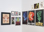 An art gallery corner showcases Matt Dyes eclectic posters and prints, including colorful illustrations, an archival pigment print of a winged figure, and fantasy-themed art. The white walls enhance the vibrant artwork, crafting a realm even Sméagol would find precious.