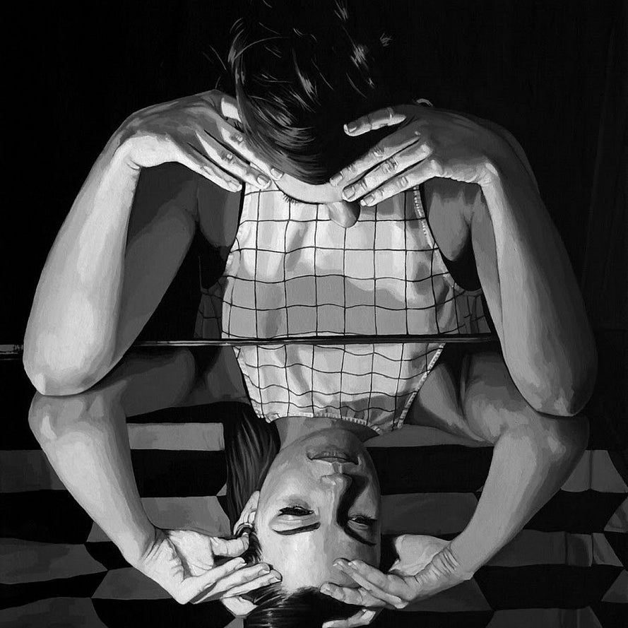A black and white image shows a person leaning over a reflective surface, their head cradled in both hands. The reflection creates a symmetrical effect reminiscent of an acrylic on canvas piece by Rebecca Adams.