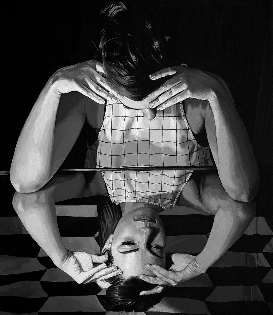 A black and white image shows a person leaning over a reflective surface, their head cradled in both hands. The reflection creates a symmetrical effect reminiscent of an acrylic on canvas piece by Rebecca Adams.
