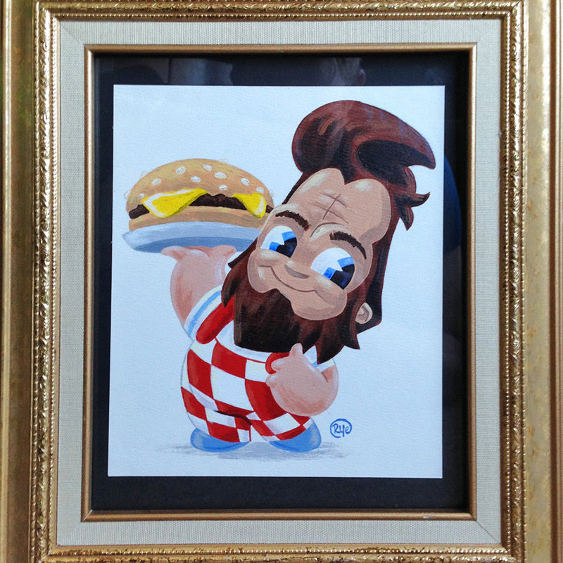 A framed painting by Ryan Hungerford features a playful cartoon character reminiscent of Big Bobs BeefSquatch from Bobs Burgers at Spoke Art NYC, with a beard, styled hair, red and white checkered outfit, holding a cheesy burger and displaying big eyes with an infectious expression.