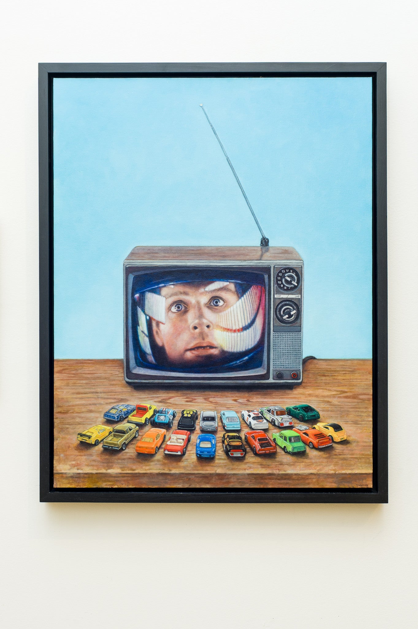 Allan Innmans oil on canvas portrays a retro TV displaying a surprised mans face. The TV, complete with an antenna, sits on wood and is surrounded by colorful toy cars meticulously arranged in three rows.