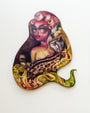The surreal artwork by Tatiana Suarez features a woman with exaggerated features, margays, and flames. Her hair merges into vibrant swirls in oil on cut-out birch set against a white background.