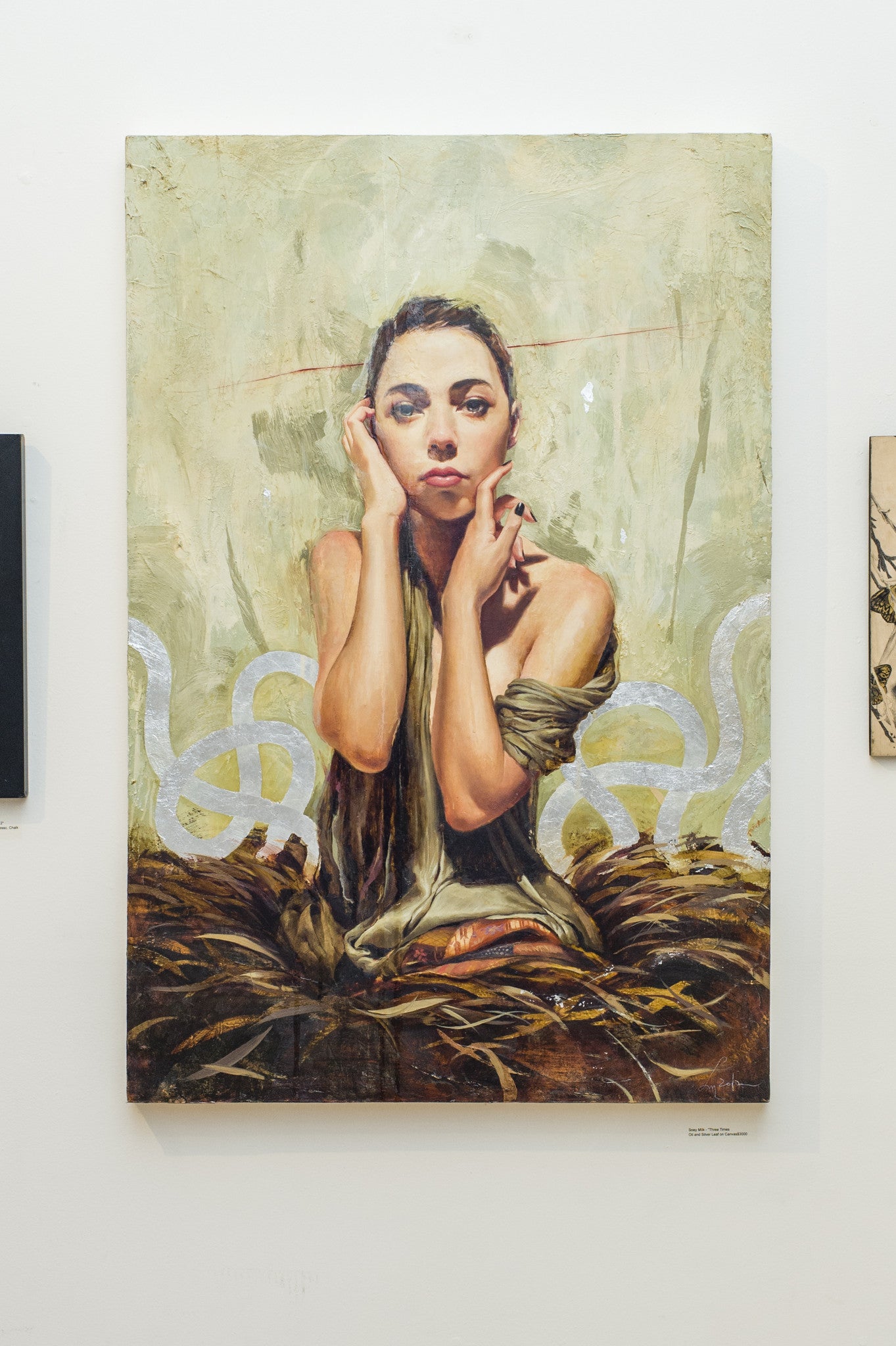 A Soey Milk painting of a contemplative woman amidst abstract shapes, her face resting on her hands. Crafted with oil and silver leaf on canvas, it showcases a textured background of muted green and earthy tones. Displayed at Spoke Art Gallery.