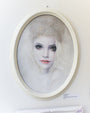 Bec Winnels captivating colored pencil portrait features a woman with long, wavy blonde hair and dark eye makeup. She wears a fur hat, elegantly showcased in an oval white frame on a white wall, labeled Evaline beneath.