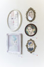 Five framed portraits of women, each in ornate frames, showcase the delicate artistry and pale color palettes reminiscent of Bec Winnel. Small labels with red dots accompany each piece, highlighting their unique charm.