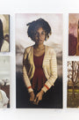 An oil on canvas by Michael Ramstead features a person with dark, curly hair in a striped cardigan over a red top against a neutral background. Its displayed in a gallery alongside other artworks, including captivating oni depictions.