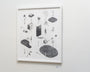 Jonas Lofgrens framed art on a white wall features abstract black and white drawings in graphite on paper, depicting tree-like shapes, ponds, a chair, and monolithic forms, creating a surreal minimalist landscape.
