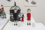 The art display features two exquisite Doubleparlour doll figures, hand-sculpted from resin, in black and red dresses with striped leggings. Each stands next to a small white animal on a pristine white platform adorned with decorative cages and other figures.