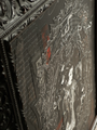 An abstract artwork, Broken Geisha No. 3 by Handiedan, features intricate gray and red mixed media patterns within a detailed frame adorned with elaborate floral and scroll motifs for a layered visual effect.