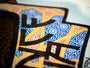 Limited edition screen print features bold black text over vibrant overlapping patterns, with an intricate geometric background in blue, orange, and white. This dynamic design echoes the distinctive style of Chuck Sperry.