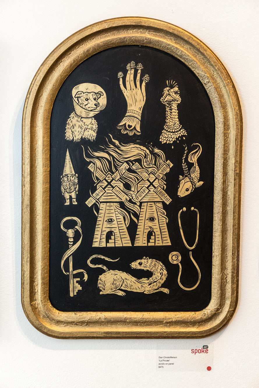 Arched artwork by Dan Christofferson features gold illustrations on a black panel, depicting a windmill, gnome, stethoscope, and more. Meticulously detailed elements are elegantly framed in gold.