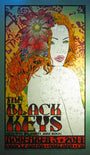 A vibrant concert poster by Chuck Sperry for The Black Keys features a floral-haired woman. It includes details of the event on November 5, 2014, at Oracle Arena, Oakland, CA, with Jake Bugg as the special guest.