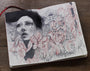 The Craww open sketchbook displays an expressive face surrounded by blooming flowers in grayscale and red tones. This graphite artwork blends seamlessly with the floral elements, set against a wooden surface background.