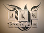 Megan Wolfes Glimmer #5 display at Spoke Art Gallery showcases abstract black and white drawings in fluid, brushstroke designs like feathers or wings, framed on a wall. A bold, swirling mural in the background enhances the exhibit.