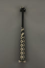 A baseball bat featuring black and white crystals and metallic spikes stands upright against a gray background. The patterns on the handle create a unique visual effect, echoing Lucien Shapiros mixed media artistry.