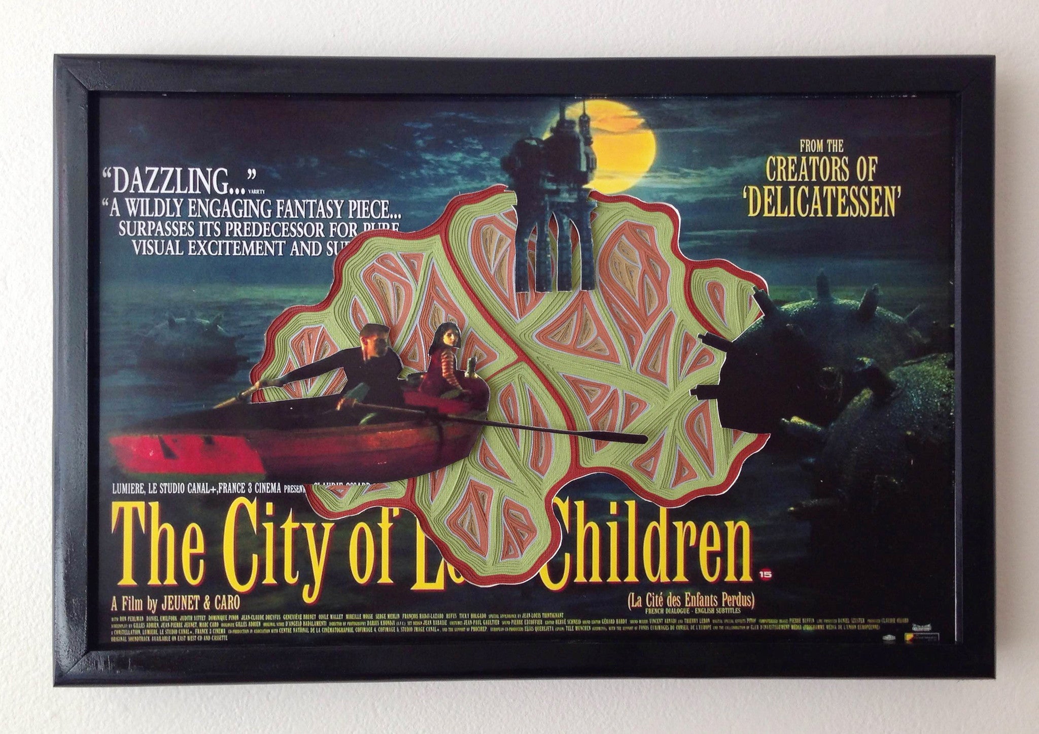 Charles Clarys reprinted poster for The City of Lost Children features two figures in a red boat against a brooding cityscape, showcasing an intricate hand-cut paper design that complements the films visually exciting style.