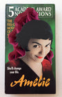 A Charles Clary stylized Amelie VHS cover features hand-cut paper art framing the leads face with black hair and red lips. The background highlights five Academy Award nominations and the tagline Shell change your life, all within a nostalgic VHS box.