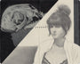 Cody Miles monochrome illustration, resembling a Moleskine sketch, shows a woman with a bun in deep thought. She wears a partially unbuttoned shirt over a top, while the dark background features a skull, adding surrealism to this graphite and ink artwork.