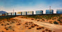 Jessica Hesss oil on canvas captures train cargo containers on a desert railway under a blue sky. The sandy foreground, dotted with shrubs and utility poles, leads to majestic mountains in the distance, reminiscent of works often showcased at Spoke Art Gallery.