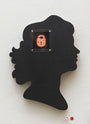 A hand-cut wood silhouette of a human head profile in black by Matt Ritchie is mounted on a light wall, featuring a whimsical red cartoon lock with a face, reminiscent of an art gallery acrylic piece.