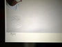 Close-up of a fine art giclee prints bottom corner showing an embossed circular logo with S and A partially visible. Below, the handwritten fraction 75/75 indicates a signed and numbered edition by Henrik Uldalen. The background is a light neutral color.