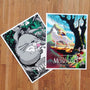 Two Joshua Budich posters are displayed on a wooden floor: one, a screenprinted Totoro masterpiece with a child in a lush forest; the other, featuring a warrior on a majestic beast among spirits. Both signed and numbered, they boast vibrant colors and intricate illustrations.