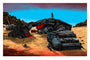 A person stands on futuristic wreckage in a desert, adorned with red flags and cloths, echoing Tim Doyles UnReal Estate series. Clear blue sky and rocky formations frame this limited edition print by the renowned artist.