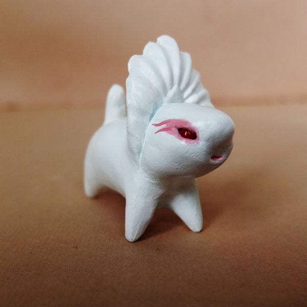The Doubleparlour hand-sculpted resin figurine showcases four legs, a ridge-like tail, and eye-catching red markings around the eyes. Its smooth, rounded form is accentuated with acrylic paint and a glossy varnish finish, presented against a plain brown background.