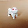 This hand-sculpted resin creation by Doubleparlour portrays Little Bashlu, a small four-legged creature with a textured face and sad expression, highlighted by striking red eyes. It gracefully stands on a light brown surface, hinting at untold stories.