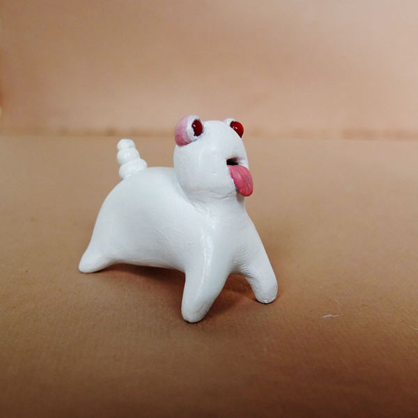 Doubleparlours charming white ceramic figurine, Little Bashlu, showcases a spiral-tailed dog with red eyes and a playful tongue against a beige backdrop, highlighting the allure of hand-sculpted resin artistry.