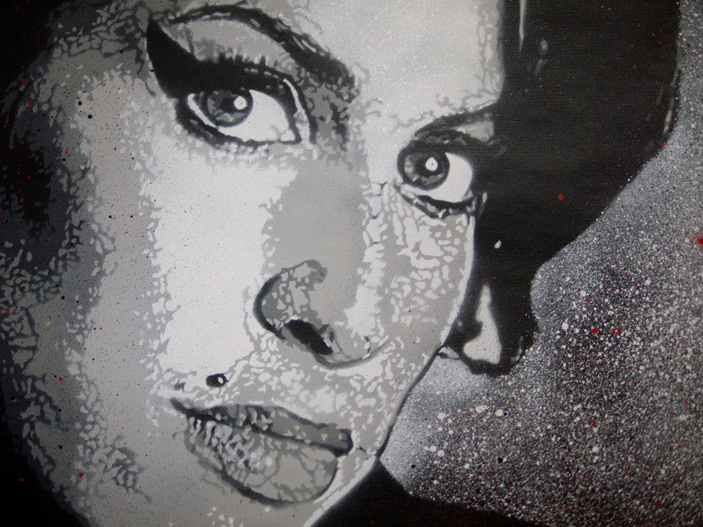 This graffiti-style artwork, inspired by Jef Aérosol, features a womans face with heavy eyeliner and a beauty mark in black and white. It evokes Amy Winehouses iconic look, enhanced by textured speckles and vibrant red splatters for contrast.
