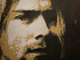 A stencil-style artwork by Jef Aérosol depicts a long-haired person with a thoughtful look, capturing Kurt Cobains enigmatic aura. It features a speckled texture in black, brown, and white shades.