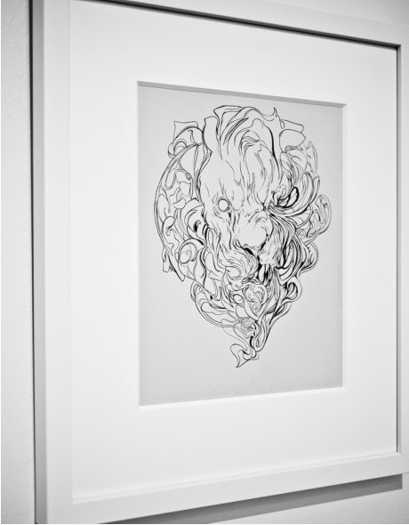A framed black and white sketch of an abstract lions head with a swirling mane, reminiscent of the Nimit Malavia style, is mounted on a wall. The expressive linework resembles intricate acrylic on paper artwork.