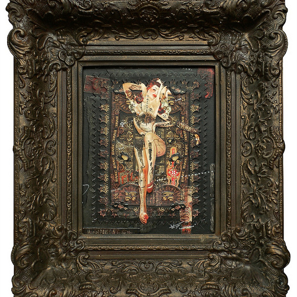 The ornate, antique frame by Handiedan showcases an intricate artwork depicting a surreal human figure with abstract patterns and textures. This mixed media collages dark palette contrasts beautifully with the detailed frame.