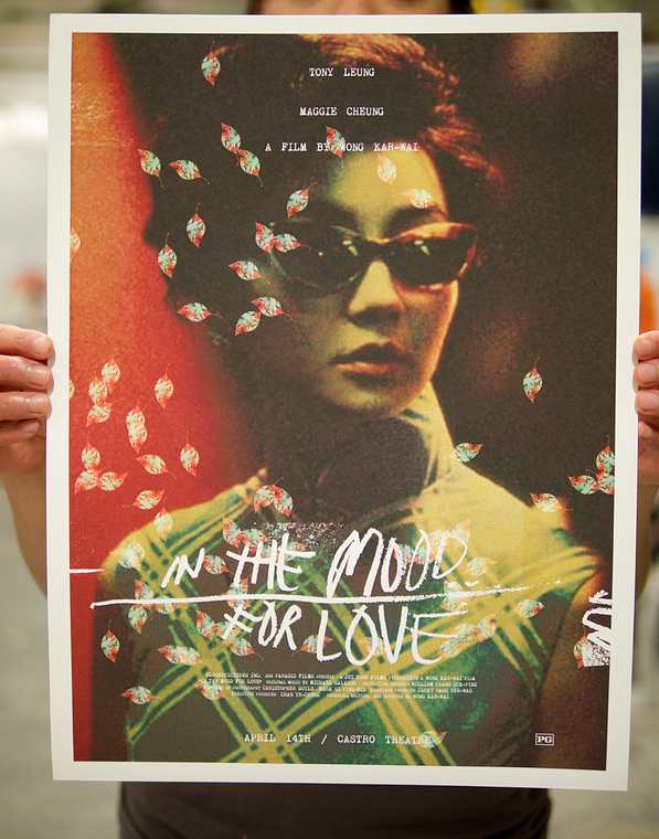 A person holds an Adam Juresko vibrant Giclee print movie poster for In the Mood for Love, featuring a character in sunglasses. Stylized floral and text elements overlay the image, highlighting actors names with a mention of Castro Theatre.