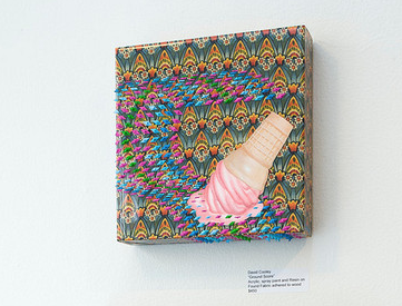 The 3D art piece Good Comedy by David Cooley features a melting ice cream cone on vibrant, patterned fabric, with striking resin details. The playful contrast between the pink ice cream and light brown cone enhances the dynamic background.